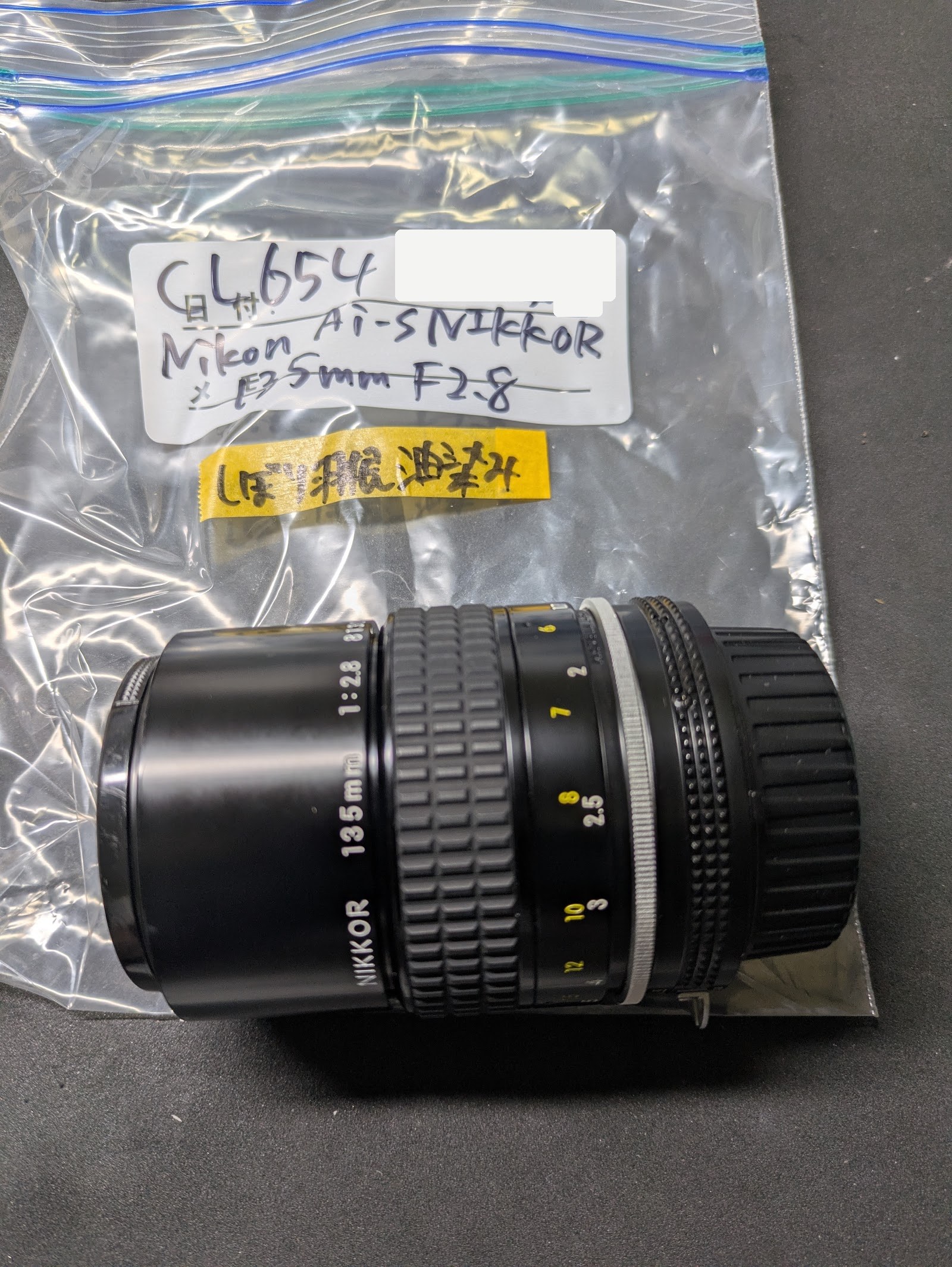 The lens in its bag with a note about oil on the aperture blades